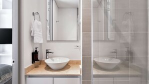 Une salle de bain moderne avec un grand miroir, deux lavabos et un espace douche.