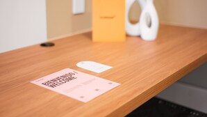 Un comptoir d’accueil en bois, agrémenté d’une carte de bienvenue, d’un vase blanc et d’une boîte placée à l’arrière-plan.