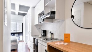 Une cuisine moderne avec des meubles blancs, un four encastré et une table à manger en bois.