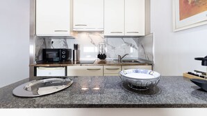 A modern kitchen with white cabinets, a granite countertop, a microwave, and a sink. - Unik Vacation Zamenhoff (Tarragona)