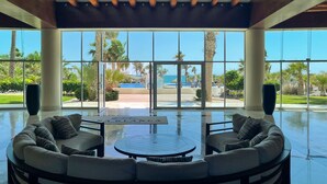 Un espacio interior amplio con ventanas grandes que ofrecen vista a una piscina y palmeras.
