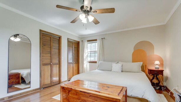 A bedroom with a bed, wooden floor, ceiling fan, and a nightstand with a lamp. - Southall Cottage: 3bd*Serene Outdoor Space* (Franklin)