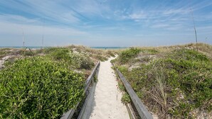 A sandy pathway flanked by dense green vegetation, leading towards a beach. - Ocean Gate I306 in St Augustine (St. Augustine)