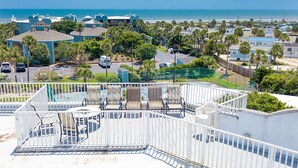 A rooftop patio with outdoor furniture, a view of the beach, and a parking area with cars. - Ocean Gate I306 in St Augustine (St. Augustine)