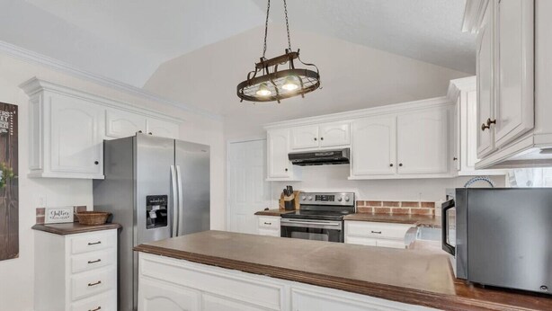 A kitchen with white cabinets, a stainless steel refrigerator, a microwave, and a wooden countertop. - Clean 3BR · Quiet Block · Backyard with Hoop (Spring Hill)