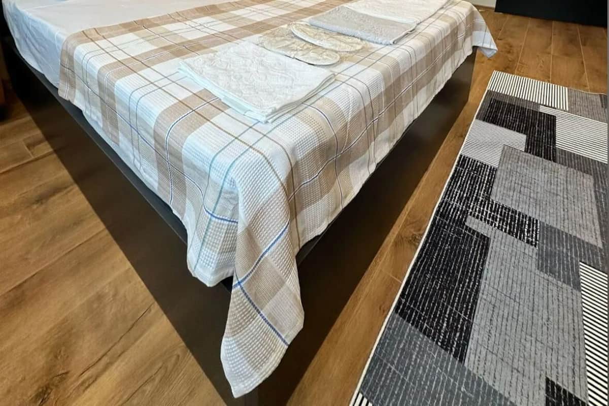 Un dormitorio moderno con una cama grande, un cabecero de listones de madera y una ducha integrada.