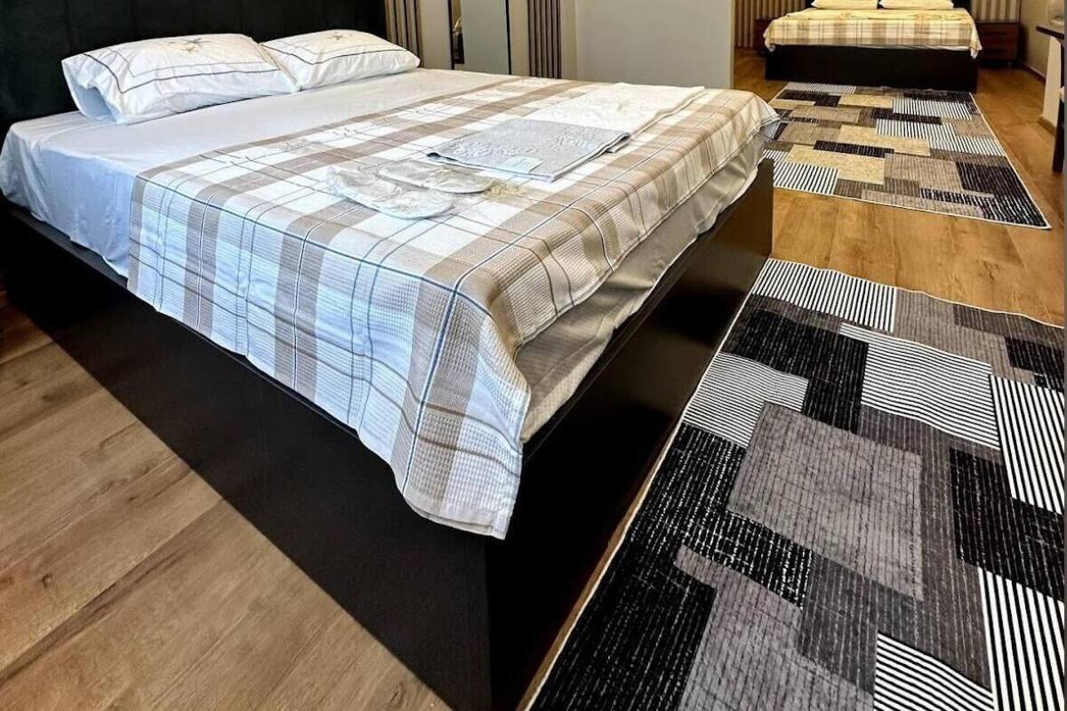 Un dormitorio moderno con una cama grande, una cama más pequeña y un espejo.