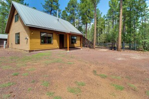 A single-story wooden cabin with a metal roof, surrounded by a gravel driveway and a fenced yard. - 1 Mi to Lake: Pet-friendly Arizona Gem (Lakeside)