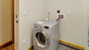 A compact, modern laundry room with a front-loading washing machine, a small electrical outlet, and a wall-mounted electrical box. - 1 Mi to Lake: Pet-friendly Arizona Gem (Lakeside)