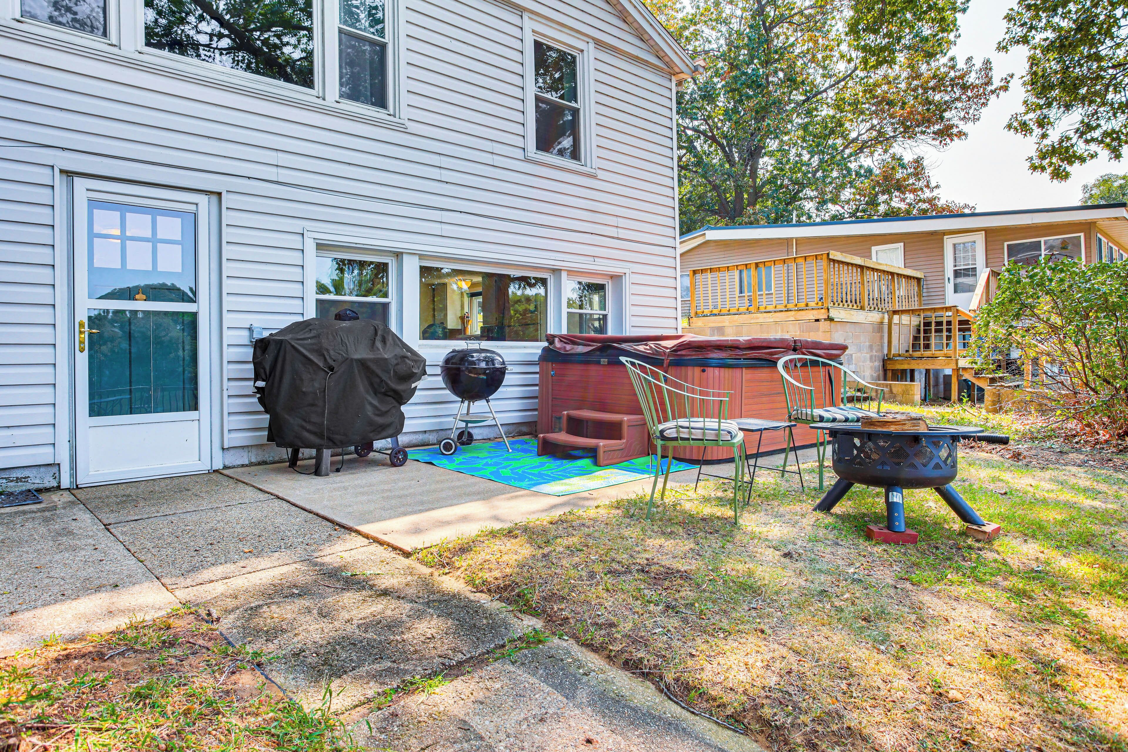 A house with a covered grill, a hot tub, and a deck.