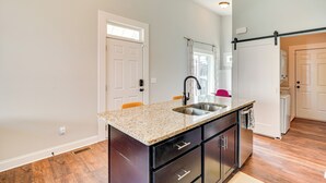 A kitchen with a granite countertop, stainless steel sink, and black cabinets. - 3 Mi to Duke: Downtown Durham Cottage! (Durham)