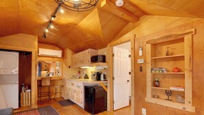Una cucina compatta con mobili in legno, un forno a microonde, un frigorifero e un angolo bar.