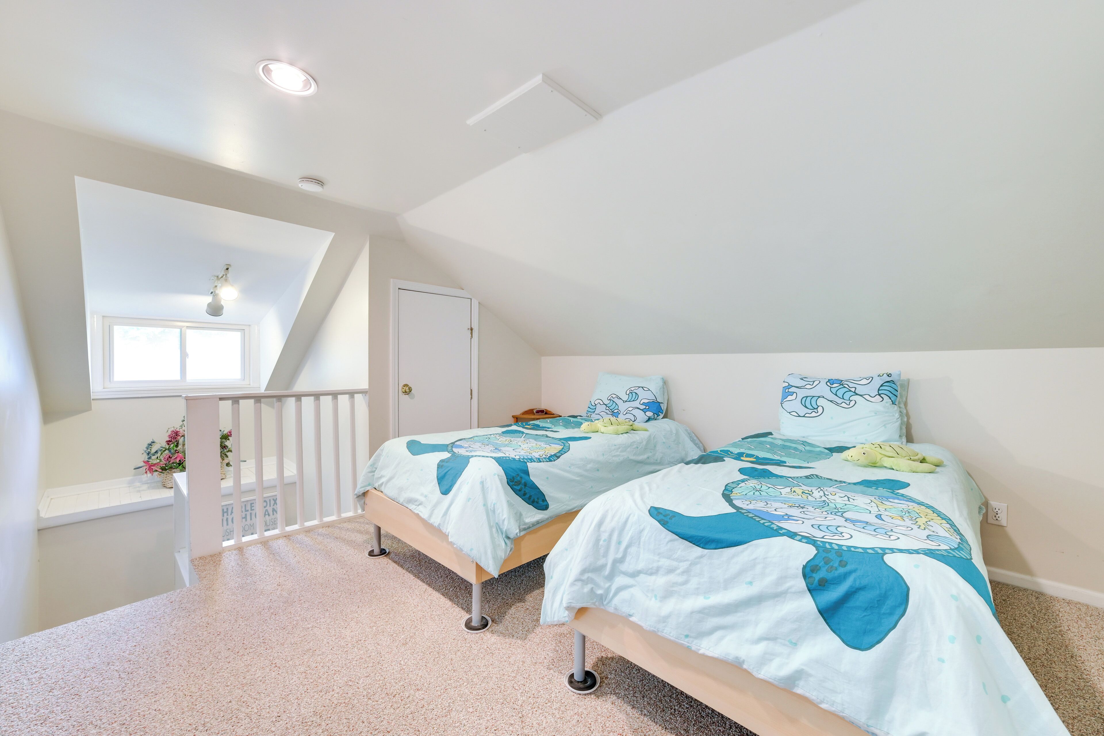 Een slaapkamer met twee bedden, een raam en een witte leuning.