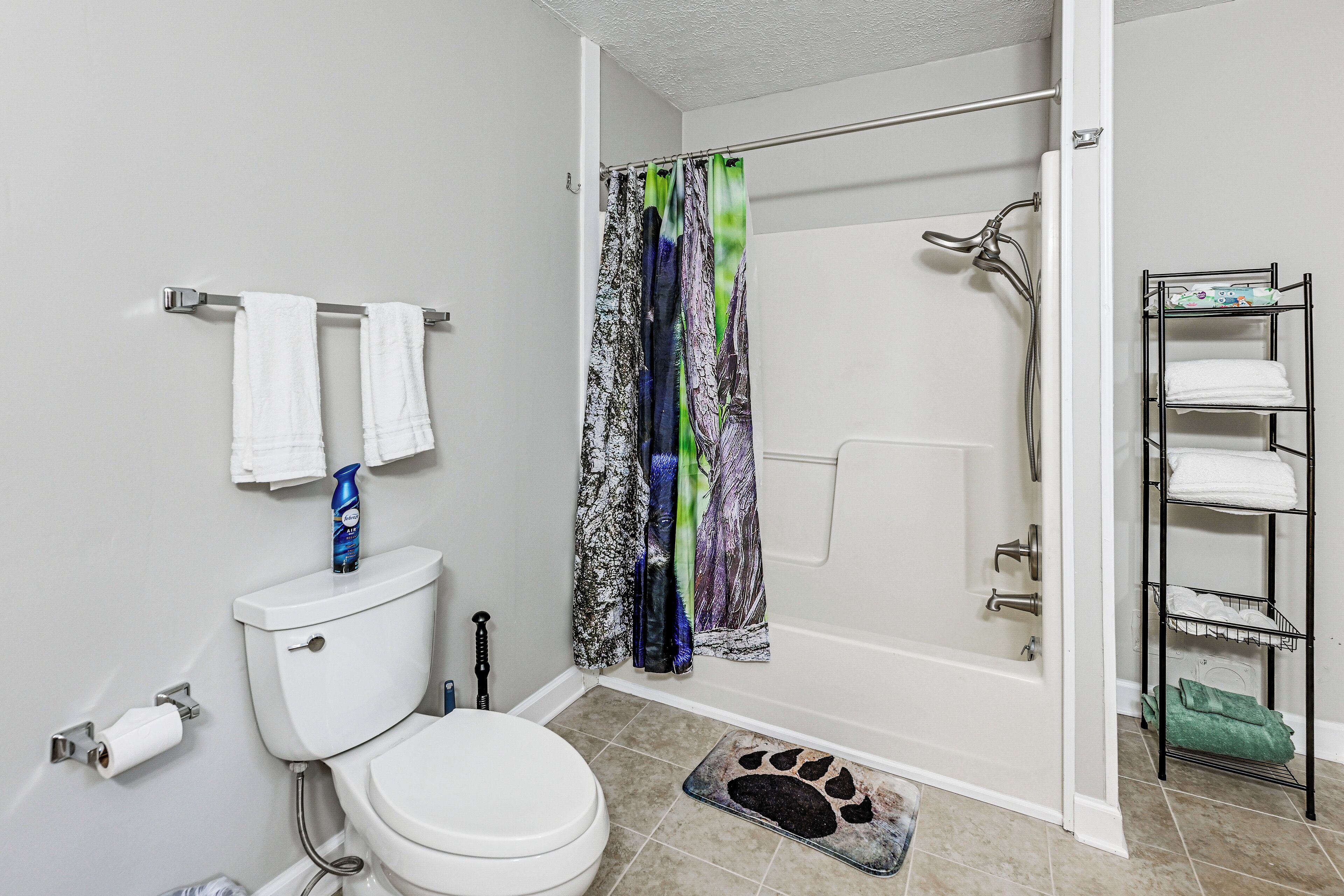 A bathroom with a toilet, a shower, and a towel rack.