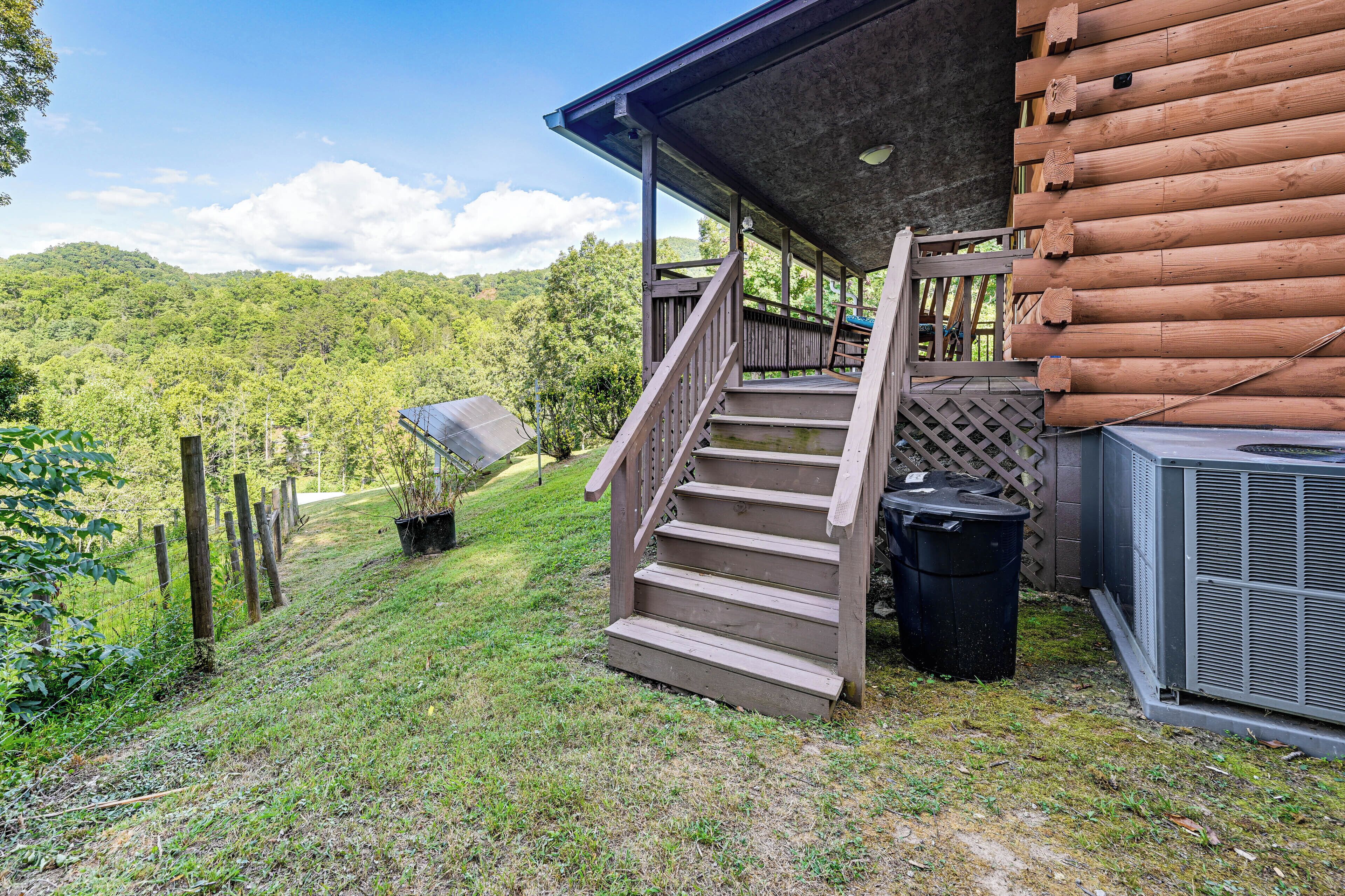 A wooden cabin with a covered porch and a staircase leading to a deck.