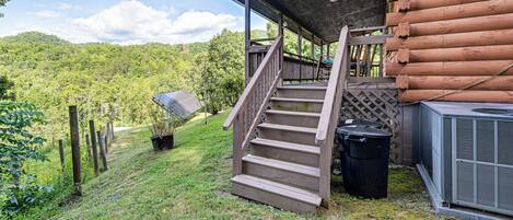 A wooden cabin with a covered porch and a staircase leading to a deck.