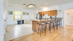 A modern kitchen with a wooden island, bar stools, and a refrigerator. - Waterfront Home w/ Boat Dock in Lake Placid! (Lake Placid)