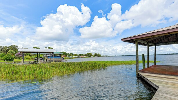 A wooden dock extending into a calm lake, surrounded by lush greenery and a clear sky. - Waterfront Home w/ Boat Dock in Lake Placid! (Lake Placid)