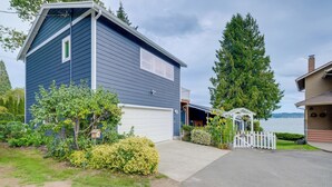 A two-story house with a garage, a covered porch, and a view of a lake. - Studio w/ Bay View: Beach Access! Octopus's Garden (Bremerton)