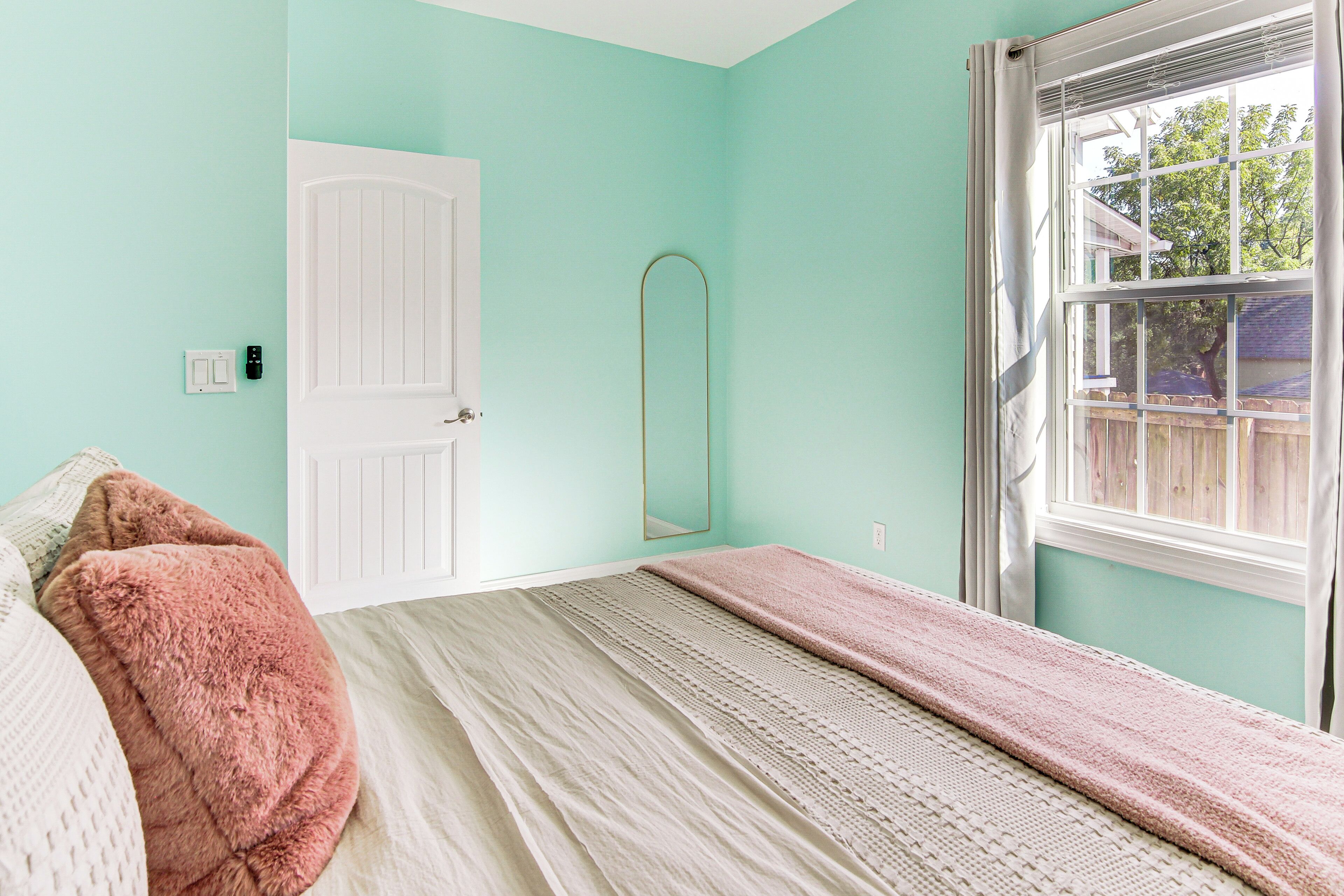 Une chambre à coucher avec un lit, une porte, une fenêtre et un miroir.
