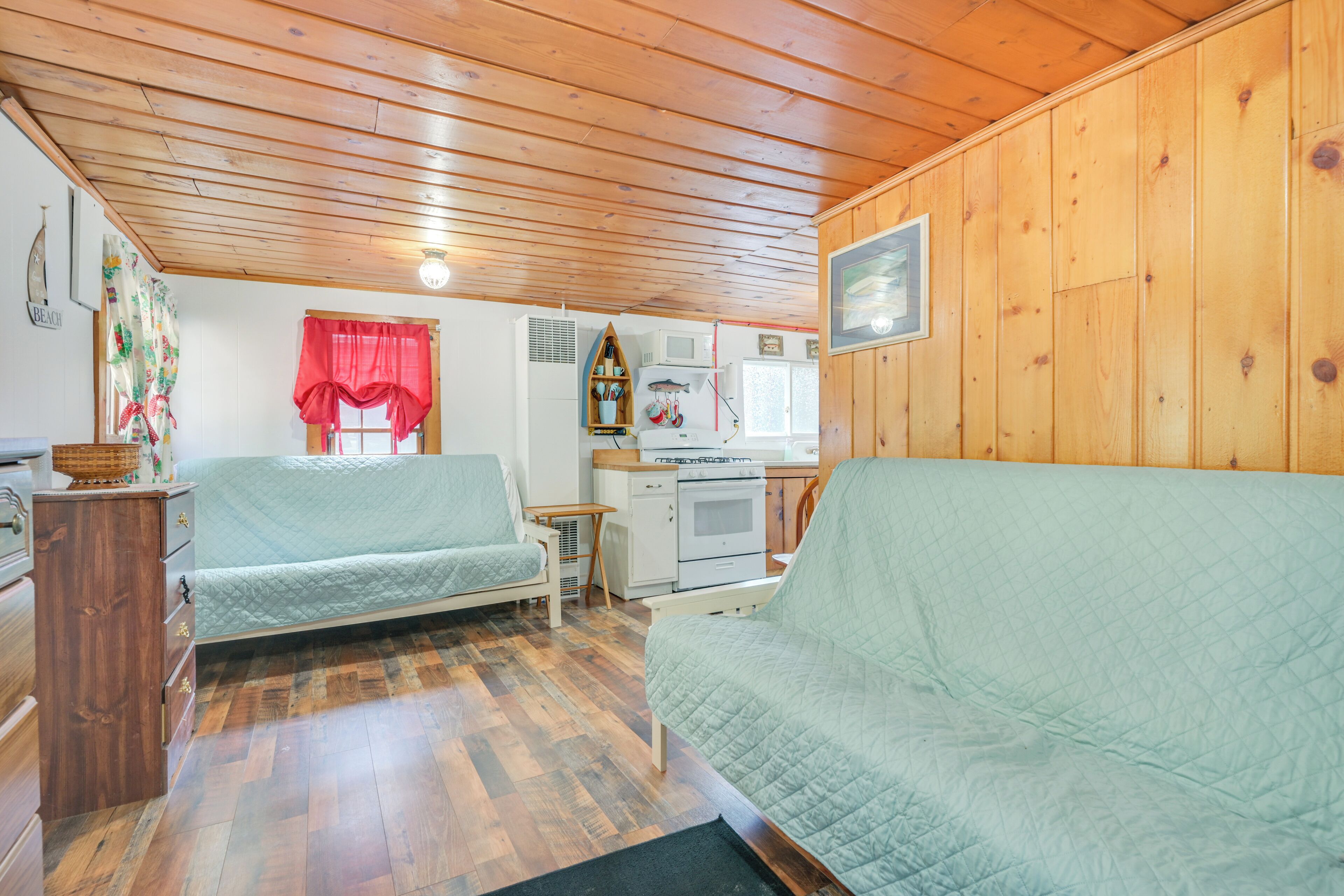 A cozy cabin-style room with two single beds, a kitchenette, and wooden walls.