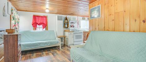 A cozy cabin-style room with two single beds, a kitchenette, and wooden walls.