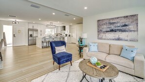 Un salon moderne avec un fauteuil bleu, un canapé beige et une table basse.