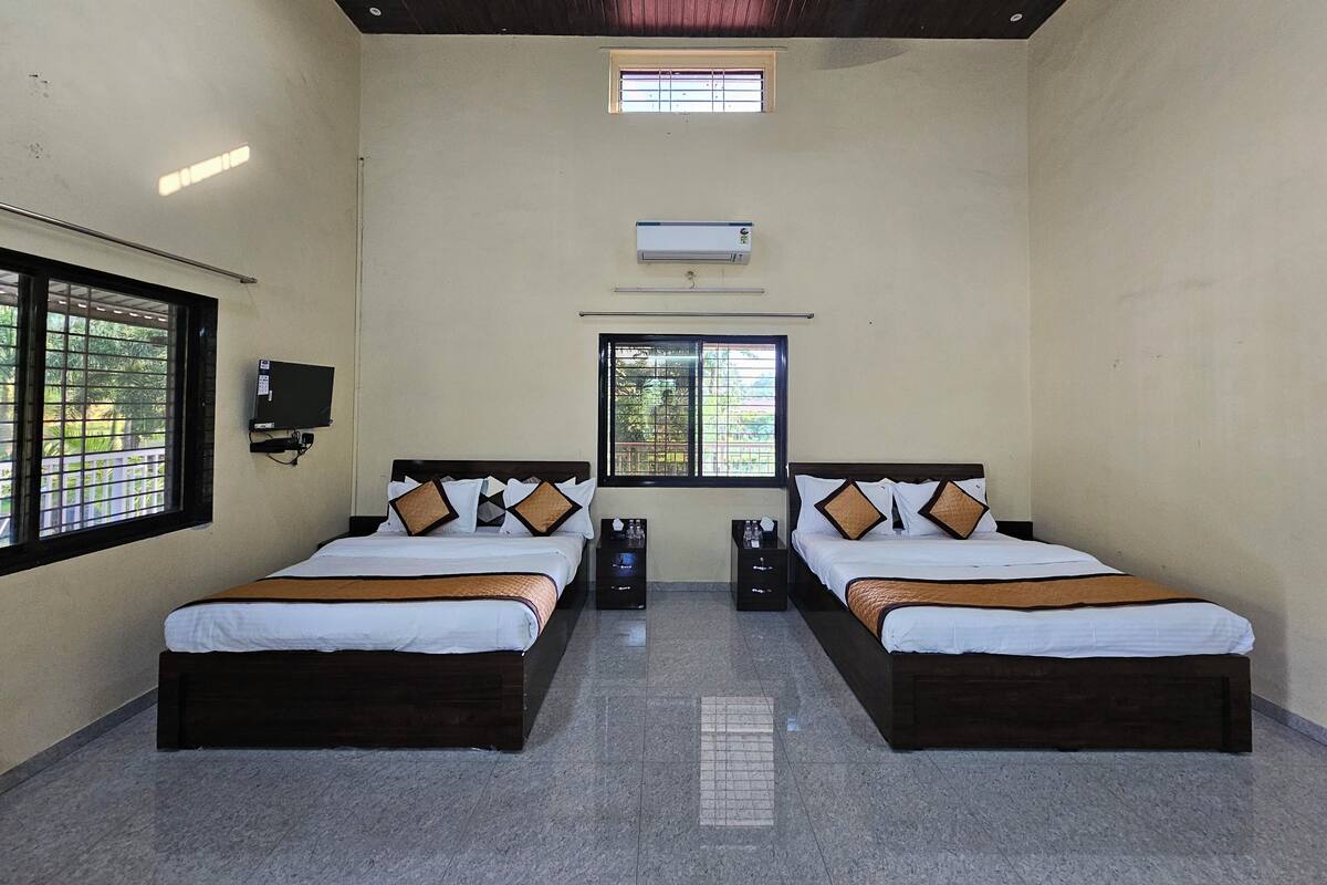 Ein Hotelzimmer mit zwei Betten, einem Deckenventilator, einer Klimaanlage und vergitterten Fenstern.