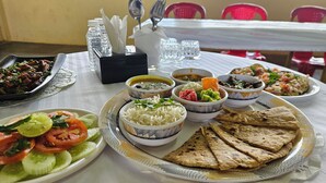 A table set with various dishes including rice, flatbreads, and salads, with condiments and utensils in the background. - Shanti Forest Resort (Karjat)