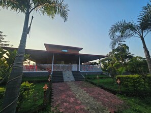 A building with a covered entrance, steps leading up to it, and a paved pathway. - Shanti Forest Resort (Karjat)