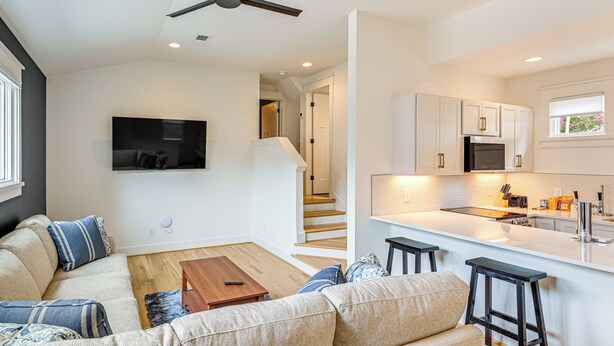 A modern living room with a sofa, coffee table, and a TV mounted on the wall. - 12 South Neighborhood: Home w/ Modern Flair! (Nashville)
