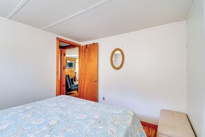 A bedroom with a bed, a wooden door, a mirror, and a bench. - Cayuga Lake , hot Tub, Private Dock (Cayuga)