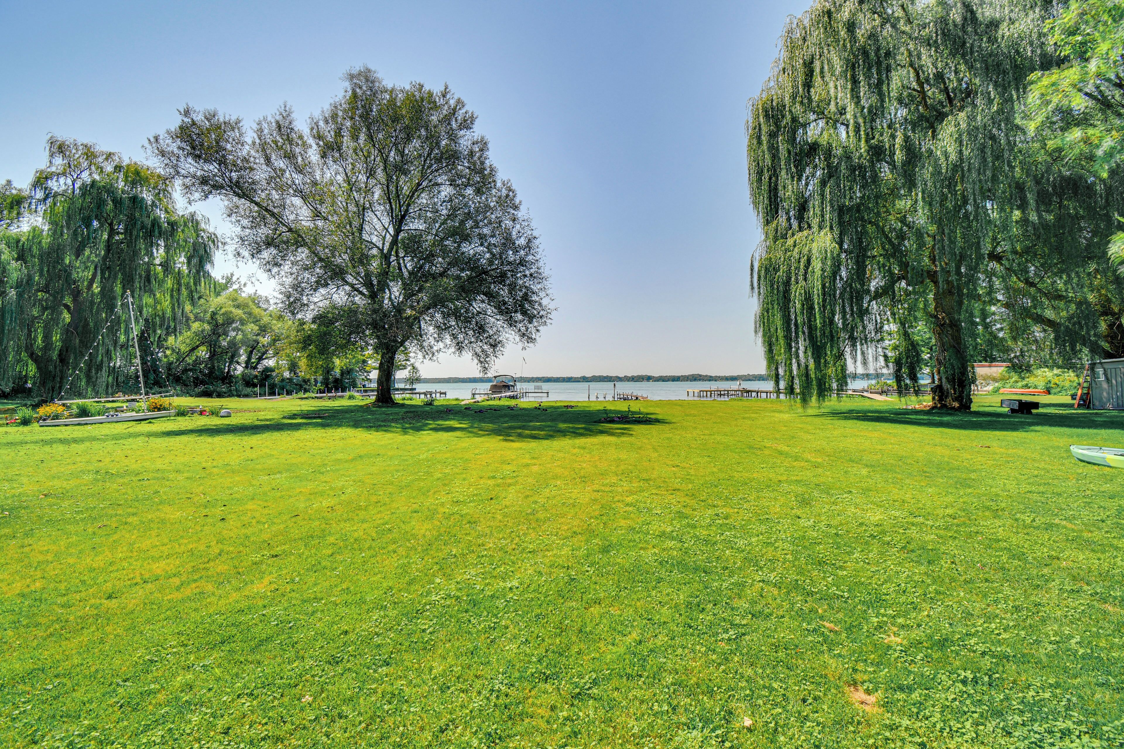 A grassy park with trees and a body of water in the background.
