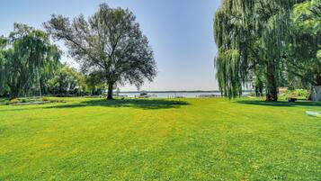 A grassy park with trees and a body of water in the background.