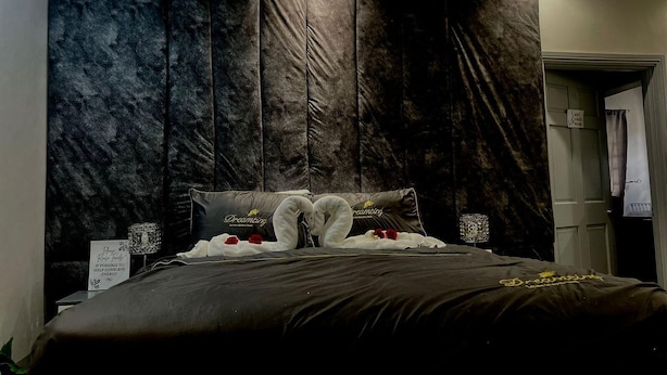 A bedroom with a dark, textured headboard, a large bed with white bedding, and decorative pillows. - Lovely Studio Apartment in Soufriere From Claviers (Soufrière)
