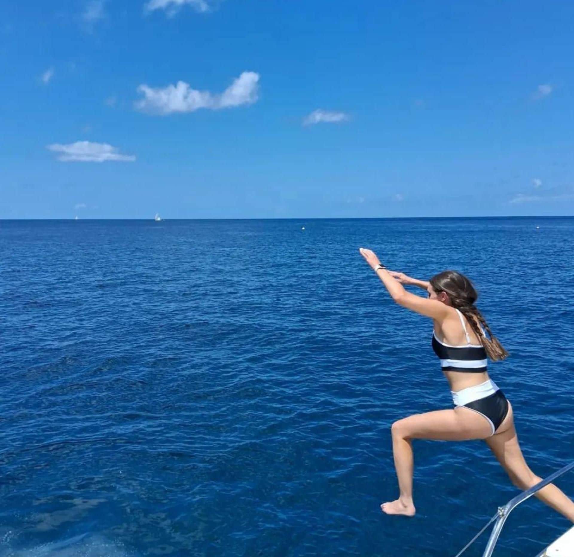 A person on a boat with a clear view of the ocean and a distant sailboat.