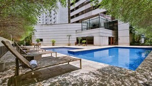 A modern building with a swimming pool, lounge chairs, and potted plants. - Get a Flat 604 - Jardim Paulista  (São Paulo)