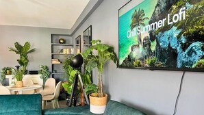 A modern living room with teal sofas, a bookshelf, and a large 'Chill Summer Lofi' poster. - Caparica Surf Retreat (Almada)