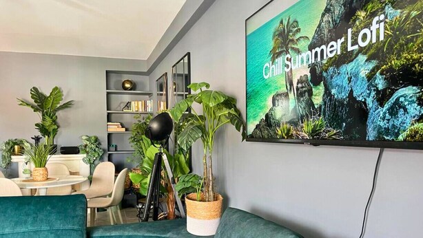 A modern living room with teal sofas, a bookshelf, and a large 'Chill Summer Lofi' poster. - Caparica Surf Retreat (Almada)