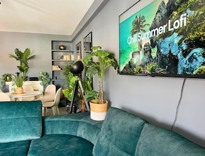 A modern living room with teal sofas, a bookshelf, and a large 'Chill Summer Lofi' poster. - Caparica Surf Retreat (Almada)
