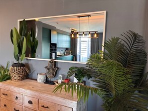 A modern kitchen with a large mirror, wooden cabinetry, and various plants. - Caparica Surf Retreat (Almada)
