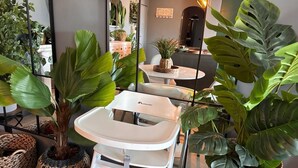 A baby changing station with wicker baskets and large green plants around it. - Caparica Surf Retreat (Almada)