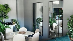 A modern dining area with a round table and chairs, a teal sofa, and large mirrors on the walls. - Caparica Surf Retreat (Almada)