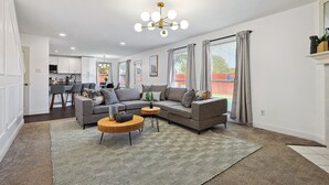 Un salon moderne avec un canapé d’angle, une table basse et un tapis à motifs.
