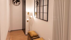 A hallway with a wooden floor, a bench with cushions, a wall-mounted mirror, and a globe decoration. - TREVI MONTI HOUSE  (Rome)