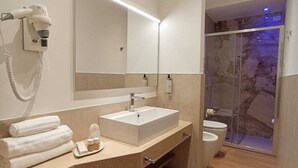 A modern bathroom with a large mirror, a sink, a hairdryer, and a shower area. - TREVI MONTI HOUSE  (Rome)