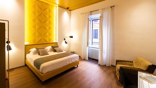 A modern hotel room with a large bed, a sofa, and a view of the street. - TREVI MONTI HOUSE  (Rome)