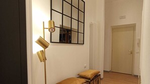 A hallway with a wooden floor, a mirrored wall, a floor lamp, and a chest of drawers with cushions. - TREVI MONTI HOUSE  (Rome)