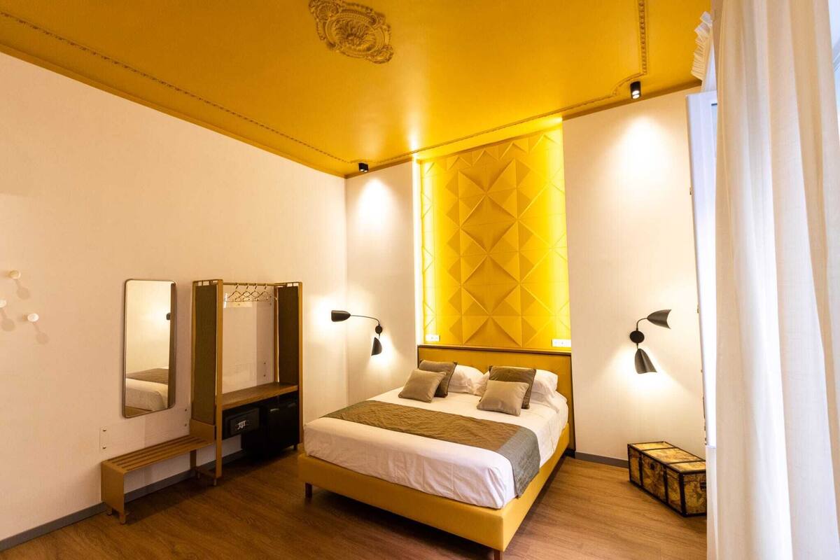A modern bedroom with a bed, bedside tables, a mirror, and a wardrobe.