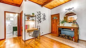 Una habitación con suelo de madera, un escritorio con silla, una chimenea y un espejo en la pared.